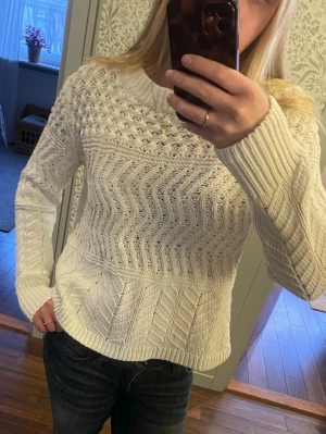 Vit stickad tröja  - Säljer en vit stickad tröja med olika strukturmönster och rund hals. Tröjan har lång ärm och ribbade muddar vid ärmslut och nederkant. Perfekt för dig som gillar en mysig och stilren look.