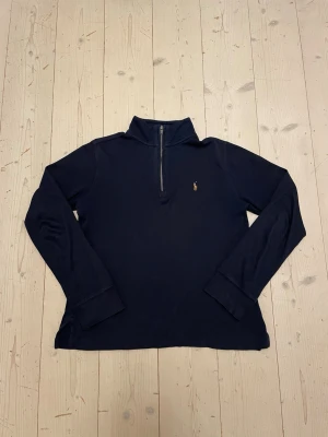 Mörkblå quarter zip från Polo Ralph Lauren 152 cm - Kan gå ner i pris 😀  152 cmMörkblå långärmad tröja från Polo Ralph Lauren med halv dragkedja och klassisk broderad logga på bröstet. Tröjan har hög krage och ribbade muddar vid ärmslut. Perfekt för en stilren och avslappnad look.