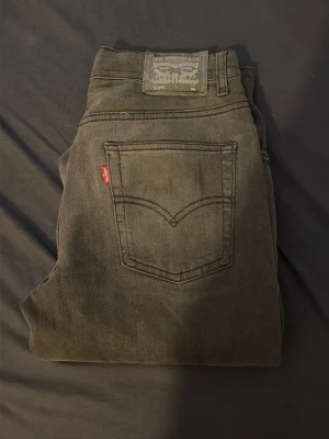 Svarta Levi's 512 Slim Jeans - Säljer ett par svarta Levi's 512 Slim Jeans med klassisk femficksdesign och röd Levi's-tag på bakfickan. Jeansen har normal midja och smal passform genom benet. Tillverkade i mjuk denim som ger en skön känsla och snygg look.