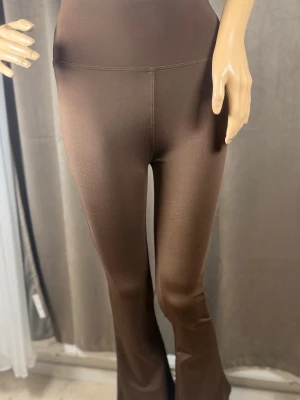 Bruna utsvängda leggings - Snygga bruna leggings med utsvängda ben och hög midja. Tillverkade i ett stretchigt och mjukt material som sitter skönt på kroppen. Perfekta för dig som vill ha en trendig och bekväm look.