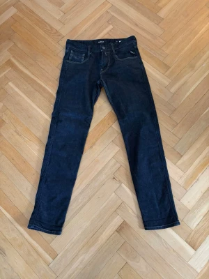 Replay jeans - Mörkblå jeans från replay med klassisk femficksdesign och raka ben. Jeansen har kontrastsömmar och subtila detaljer på bakfickorna. Perfekta för en stilren och avslappnad look. Storlek 29/32. 