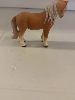 Brun hästfigur i plast - Säljer en brun hästfigur i plast med ljus man och svans. Hästen har realistiska detaljer och är perfekt som prydnad eller leksak. Passar dig som gillar djur eller samlar på figurer.