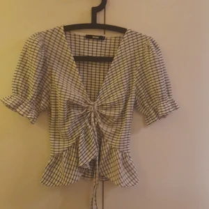 Randig blus från Bik Bok - Säljer en söt randig blus från Bik Bok i storlek XS. Blusen har korta ärmar och en knytning framtill som ger en fin detalj. Perfekt för en avslappnad stil.