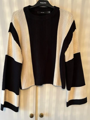 Randig stickad tröja från Vero Moda strl M - Snygg stickad tröja från Vero Moda med breda svarta och vita ränder. Tröjan har en boxy, croppad passform och vida ärmar. 