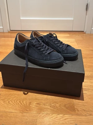 Skolyx Mörkblå mockasneakers - Stilrena mörkblå sneakers i mocka med matchande mörkblå skosnören och gummisulor från Skolyx. Insidan är fodrad i ljusbrunt läder för extra komfort. Perfekta för dig som gillar en clean och klassisk look. Nypris 1699kr. Skokartong och påse ingår. Priset är inte hugget i sten.