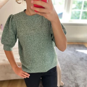 Grön stickad tröja från Vero Moda - Superfin ljusgrön stickad tröja från Vero Moda med puffiga halvlånga ärmar och rund halsringning. Mjuk och skön, perfekt till både jeans och kjol. Tröjan har ribbade muddar och en snygg, enkel design som känns modern och fräsch. 