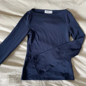 Mörkblå långärmad topp Weekday - En stilren mörkblå långärmad topp från Weekday med rund halsringning. Tillverkad i mjuk bomull som sitter skönt mot kroppen. Perfekt att matcha med jeans eller kjol för en clean look.