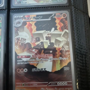 キョジオーン - Coolt japanskt Pokémonkort med häftig illustration av en stenliknande Pokémon i en vulkanisk miljö. Perfekt för samlare och fans av Pokémon som vill ha något unikt i sin samling!