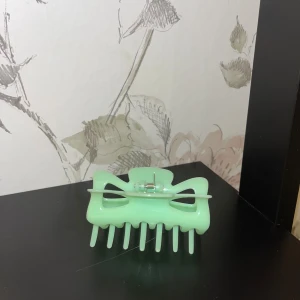 Mintgrön hårklämma med öppna detaljer - Snygg mintgrön hårklämma i plast med öppna detaljer och robust metallfjäder. Perfekt för att snabbt sätta upp håret och ge en fräsch touch till din look. Klämman har en modern form med breda taggar som håller håret på plats.