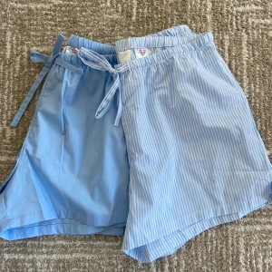 Blå och blåvit randiga shorts H&M XS - Två par mjuka pyjamas shorts från H&M i storlek XS. Ena paret är ljusblå och det andra har blåvita ränder. Båda har elastisk midja och snörning framtill. Perfekta för chill dagar eller som pyjamasshorts. Tillverkade i 100% bomull för skön känsla och perfekta nu inför hösten! Helt nya, behövde dra av prislappen för att testas då dom satt ihop, passade ej så därför säljs dom nu. Nypris: 200