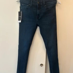 Jack & Jones Skinny Liam jeans blå - Mörkblå skinny jeans från Jack & Jones, modell Liam. Klassisk femficksdesign med smal passform och normal midja. Tillverkade i stretchigt denim för en bekväm känsla. Perfekta för dig som gillar en tight och modern look. Köpta via Jack and Jones hemsida för 499kr, helt nya, säljer då dem inte passade mig!