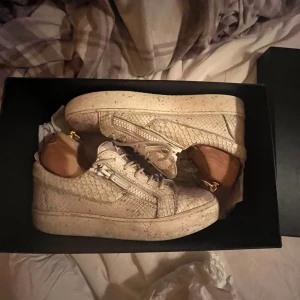 Giuseppe Zanotti skor - Säljer ett par sneakers från Giuseppe Zanotti i beige skinn med ormmönstrad struktur. Skorna har snörning, dragkedja på sidorna, tvär feta för dig som vill sticka ut✨ca~6000kr nypris