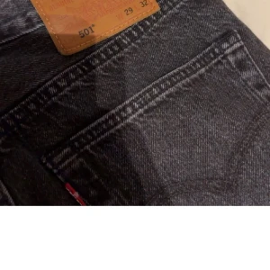 Levi's 501 svarta jeans straight fit - Klassiska svarta Levi's 501 jeans med rak passform och femficksdesign. Jeansen har en snygg mörk tvätt och är tillverkade i slitstarkt denim. Perfekta för dig som gillar en tidlös och clean look. Ikonisk läderpatch bak i midjan och röd Levi's-tagg vid bakfickan.