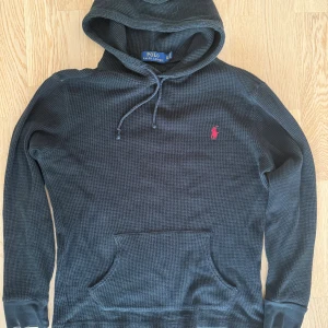Svart hoodie från Polo Ralph Lauren  - Svart hoodie från Polo Ralph Lauren i storlek XS. Tröjan har huva med snörning, långärmade ärmar. Materialet är bomull med en grovstickad struktur och den ikoniska röda Polo-loggan broderad på bröstet. Skick 9/10 För fler frågor kom pm! /Neo