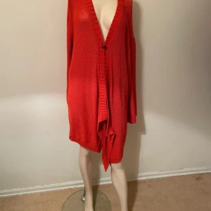 Orange oversized stickad kofta - Säljer en röd oversized stickad kofta med djup v-ringning och lång ärm. Koftan har en lös passform och stängs med en liten hake framtill. Perfekt att slänga över en outfit för en chill look storlek M/L även passar XL