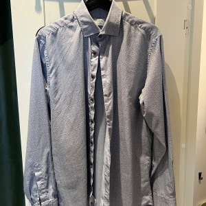 Mönstrad skjorta från Stenströms - Snygg skjorta från Stenströms i storlek 40 med diskret geometriskt mönster i grått och beige. Skjortan har klassisk krage, långa ärmar och knappar framtill. Perfekt för dig som gillar stilrena detaljer och vill sticka ut lite extra.