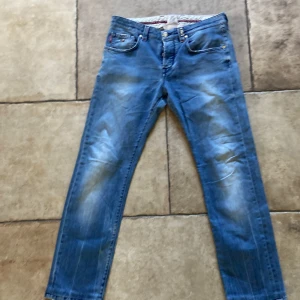 Blå jeans från Tramarossa med röda detaljer - Snygga blå jeans från Tramarossa med coola röda sömmar och guldiga knappar. Klassisk femficksmodell med unika detaljer och modern passform. Jeansen har en stilren look och är tillverkade i mjukt denimtyg som sitter skönt hela dagen. Jeansen är i mycket fint skick är slim fit smat W32.