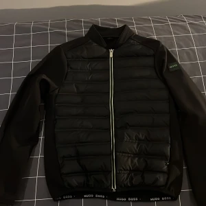 Hugo boss vindjacka  - En svart vindjacka från Hugo boss, den är i mycket bra skick och den är väldigt snyggt till t.ex ortenstil. Den ger inte av för mycket och skriker orten men den är clean 