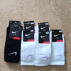 Nike Elite Cushloned strumpor - Nike Elite Cushloned strumpor i svart och vitt med broderad Swoosh-logga. De vita har lila logga och de svarta har vit logga. Ribbad design för extra komfort. Perfekta för dig som vill ha sportig stil och mjuk känsla. Storlek (svart):41-46. De vita: One-Size. PRISET GÄLLER ENDAST FÖR 1 PAR. Det går också att göra paket om man nu så vill för att sänka pris. 3 för 2 NU