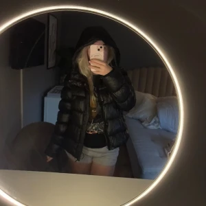 Svart pufferjacka med huva, EU 38 - Säljer en svart pufferjacka i storlek EU 38. Jackan har en glansig finish, huva och dragkedja framtill. Passformen är normal och jackan är vadderad för extra värme. Märket är superdy 💗prutbart