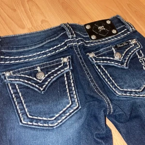 Mörkblå Miss Me jeans - Snygga mörkblå jeans från Miss Me (ny produktion) med tydliga vita kontrastsömmar och dekorativa fickor bak. Bootcut-modell med låg midja. Jeansen är uppklippta till att passa någon runt 150cm, säljer då dom var lite för korta för mig. Inte mina bilder utan tjejen jag köpte ifråns bilder 💗