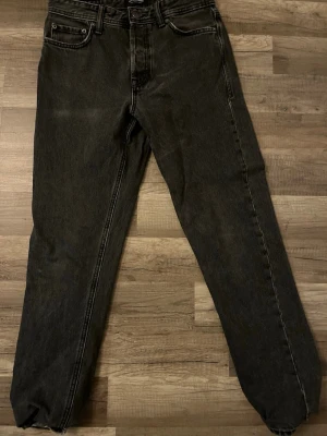 Svarta straight jeans från Jack & Jones - Snygga svarta jeans från Jack & Jones i klassisk straight modell. Jeansen har fem fickor, bälteshällor och knappgylf. Materialet är robust denim i bomull och passformen är normal med raka ben. Storlek 28/32. Skick 7/10.