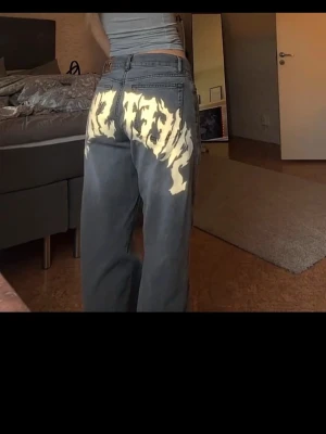 Sweet SKTBS jeans  - Cool and unique jeans from Sweet SKTBS in size XXS. Grey/washed denim with a standout white flame-style graphic on the back, giving them a bold streetwear/skate vibe. Classic 5-pocket design with a relaxed, straight-leg fit.  In good condition with normal signs of wear. Perfect for anyone into Y2K, skate, or street style. bought from Junkyard, new price 1249kr