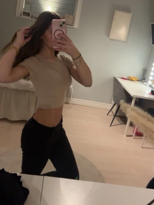 Beige croppad t-shirt - Säljer en enkel och stilren beige croppad t-shirt med rund hals och korta ärmar. Perfekt att matcha med höga jeans eller kjol för en trendig look. Materialet känns mjukt och stretchigt, vilket gör den bekväm att bära hela dagen.