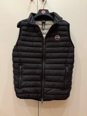 Svart dunväst från Colmar - Svart dunväst från Colmar med quiltad design och två dragkedjeförsedda fickor framtill. Västen har hög krage och Colmar-logga på bröstet. Perfekt för lager-på-lager och håller dig varm under kyliga dagar. Priset kan diskuteras👍