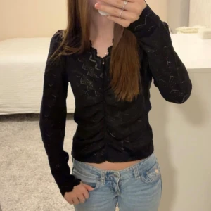 Svart långärmad topp med rynk - Säljer en svart långärmad topp med snygg rynkning framtill. Toppen är croppad och har ett lite diskret glittrigt material. Använd endast 1 gång💕