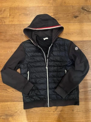 Svart Moncler cardigan med huva - •Skick 7,5/10 (Finns hål på ärmen som går att sy) •Pris: 1999kr🔥(p.g.a hålen) •Strorlek M/S. Kom dm vid eventuella frågor🤲