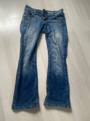 Blå bootcut jeans från ONLY - Snygga blå bootcut jeans från ONLY med klassisk femficksdesign och dubbla knappar i midjan. Jeansen har en lätt tvättad look och är tillverkade i jeansmaterial med skön passform. W34 L34