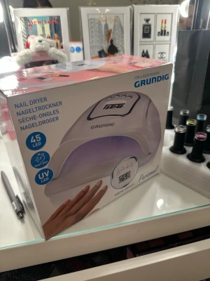 Nageltork Grundig UV LED uv-lampa - Nageltork från Grundig med 45 UV LED-lampor och digital display. Vit, kupolformad design med timerfunktioner (10, 30, 99 sekunder) och low heat-läge. Perfekt för att snabbt torka nagellack och gelé. Enkel att använda och passar alla nageltyper. Väldigt bra skick, lite rester av rött nagellack bara!