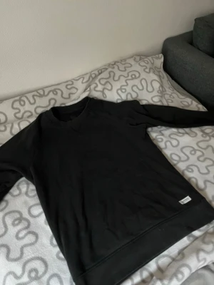 Svart sweatshirt från Lager 157  - En stilren svart sweatshirt från Lager 157 med rund halsringning och ribbade muddar vid ärmslut och nederkant. Perfekt basplagg som funkar till det mesta och är riktigt skön tack vare mjukt material.