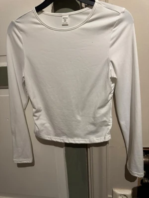 Vit långärmad topp från SHEIN - Klassisk vit långärmad topp från SHEIN med rund halsringning. Tillverkad i mjuk bomullsmix som är skön mot huden. Enkel och stilren design som funkar till många olika outfits.
