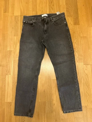 Grå jeans från Calvin Klein Jeans - Säljer ett par klassiska grå jeans från Calvin Klein Jeans. Modellen har raka ben, fem fickor och silverfärgade detaljer. Jeansen är tillverkade i denim och har en snygg, mörkgrå tvätt som passar till allt.
