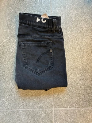 Svarta dondup jeans i modellen George  - Säljer ett par svarta skinny jeans från dondup med klassisk femficksdesign och diskreta sömmar. Jeansen har en smal passform och är tillverkade i mjukt denimtyg som sitter snyggt. Perfekta för dig som gillar en stilren och enkel look.