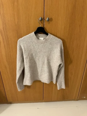 Beige stickad tröja med rund hals - Säljer en beige stickad tröja med rund hals och ribbade detaljer. Tröjan har en loose passform och långa ärmar från H&M i storlek xxs