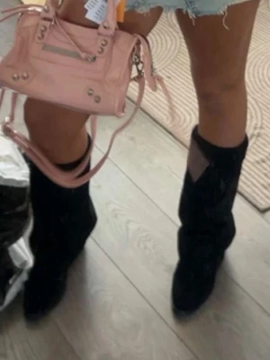 Svarta boots i mocka med spetsig tå - Säljer ett par svarta boots i mjuk mocka med spetsig tå och låg klack. Snyggt slouchy skaft som ger en cool vibe och passar perfekt till jeans eller kjol. Platt sula för skön komfort hela dagen.