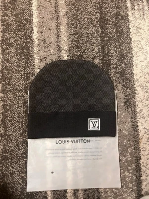 Svart rutig mössa - Snygg svart mössa med diskret rutigt mönster och uppvikt kant. Mössan är tillverkad i mjukt material som känns lyxigt och passar perfekt för kalla dagar.hör av er vid frågor(passar perfekt i alla storlekar och är inte för stor, visar bild på en nöjd kund när han har på sig den:)