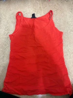 Röd linnetopp från H&M, storlek S - Säljer en enkel och snygg röd linnetopp från H&M i storlek S. Toppen är ärmlös med klassiska smala axelband och har en rundad halsringning. Perfekt för varma dagar och lätt att matcha med jeans eller shorts.
