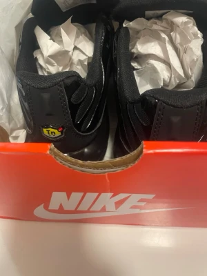 Nike Air Max Plus Tn Svarta sneakers - Jag säljer helt oanvända Nike Air Max Plus Tn sneakers i helsvart färg med Tn Air-detalj på hälen och sulan. Skorna har en snygg mesh- och syntetöverdel, robust platt sula och klassisk snörning. Ikonisk design med vågiga linjer och synliga Air-enheter i sulan.