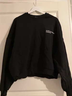 Svart sweatshirt från NLY Trend - Svart sweatshirt från NLY Trend i storlek L. Tröjan har rund hals, långärmade ärmar och ett litet vitt tryck med texten 'HI-TECH CITY NETWORK' på bröstet. Materialet är mjuk bomull och passformen är loose för en avslappnad stil. Säljer även ett par tillhörande mjukisbyxor i en annan annons. 💗