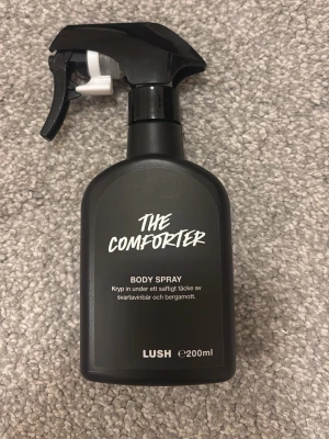 The Comforter Body Spray 200ml - Body spray från Lush med doft av svartvinbär och bergamott. Fräsch och fruktig doft med tydliga toner av svartvinbär och en lätt, uppiggande citrus från bergamott. En mild body spray som passar bra till vardags.Volym: 200ml.  Det som är kvar i flaskan visas på bilden.