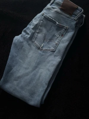 Replay Anbass  - Säljer ett par Replay Anbass jeans med snygga slitningar storlek W32 L30. Finns en LITEN defekt under gylfen jag kan skicka bild på men som är lätt att bara sy igen! 