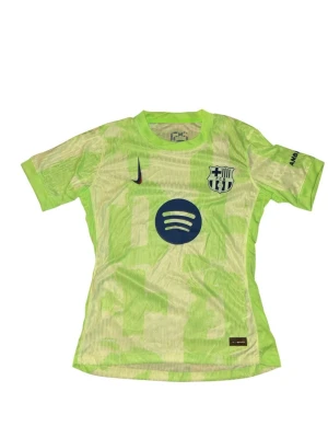 Barcelona tröja - Bilderna visar en Barcelona fotbollströja i ljusgrön färg med Nike-logga och Spotify-tryck, men inga skor finns med.