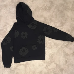 Svart Denim Tears Hoodie - En svart denim tears hoodie med mörk gråa blommor på i storlek S. Denna hoodie är äkta köpt i usa och har stock ex passerande kvalitet.
