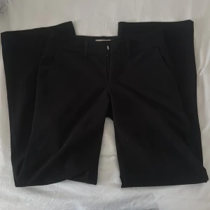 Svarta kostymbyxor från Alobha Label - Säljer ett par svarta kostymbyxor från Alobha i storlek XS. Byxorna har raka, vida ben och klassisk passform med hällor för bälte, fickor och dragkedja med knappstängning. Perfekta för en clean och stilren look. OBS en knapp ha är lossnat på ena bakfickan, men påverkar inte själva byxan