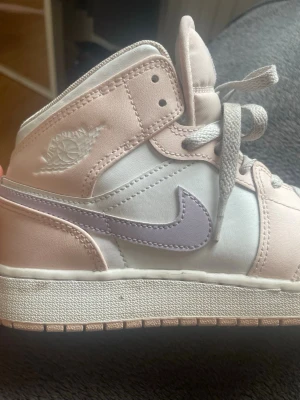 Nike Jordan rosa/vit sneakers🫶🏻 - Säljer ett par Nike Jordan 1 High sneakers i storlek 37.5. Skorna har en snygg kombination av ljusrosa och vit med lila swoosh, högt skaft och klassisk snörning. Materialet är skinn och textil, med perforerad tå och mjuk plös med Air Jordan-logga. Original boxen kommer med!🤍
