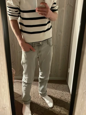 Vit och marinblå randig tröja Lindex - Säljer en vit stickad tröja från Lindex med marinblå horisontella ränder. Tröjan har lång ärm, ribbade muddar och en half zip vid halsen. Perfekt för dig som gillar klassisk stil med lite marint vibe. Passar dig som vill ha en normal passform.